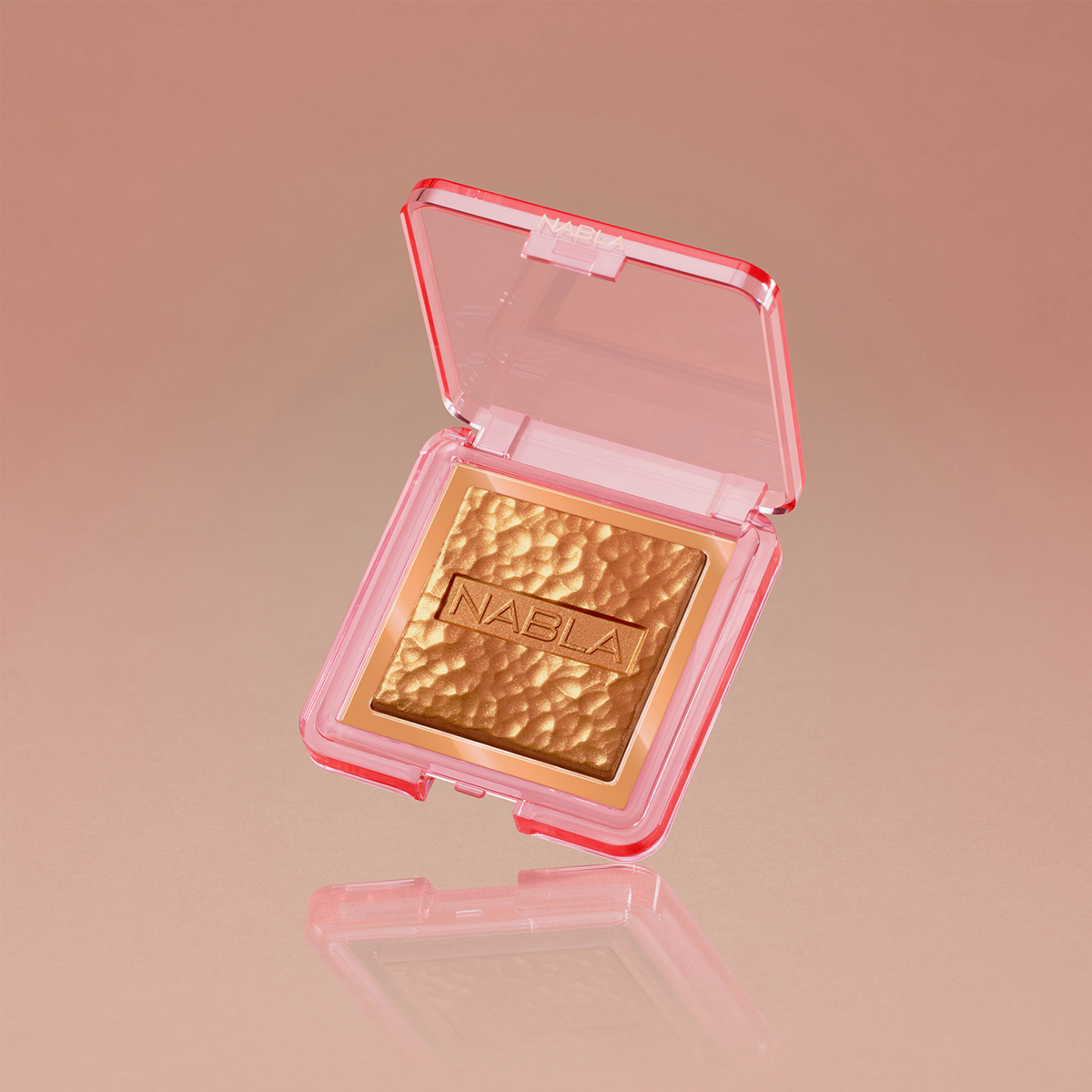 Der goldene Highlighter Skin Glazing befindet sich in einem kompakten rosa Etui und wird auf einem reflektierenden pfirsichfarbenen Hintergrund präsentiert.