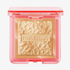 Skin Glazing in Amnesia ist ein goldener Puder-Highlighter in einer rosafarbenen, transparenten Kompaktdose mit der Bezeichnung NABLA.