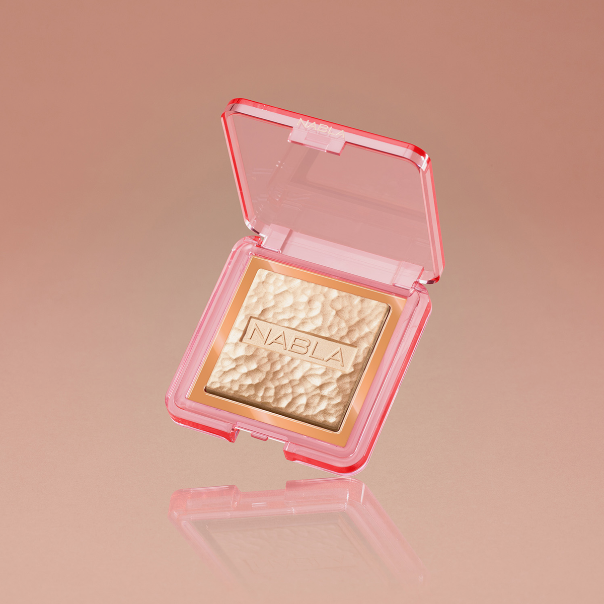 NABLA Skin Glazing ist ein strukturiertes, goldfarbenes Kompaktpuder in einer rosafarbenen Hülle, das mit dem Markenlogo geprägt und auf einem beigen Hintergrund abgebildet ist.