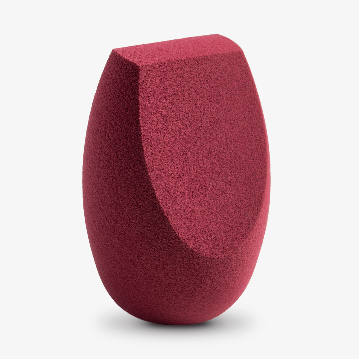 Der Flawless Precision Makeup Sponge mit flacher Kante und abgerundeter Basis in Rot steht aufrecht auf einem weißen Hintergrund.
