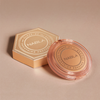 Runder, transparenter Puder mit NABLA-Logo und sechseckige, goldene Box mit der Aufschrift „Close-Up Smoothing Pressed Powder“ auf beigem Grund.