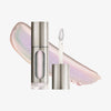 Eine teils silberne und teils transparente Tube Vision Flush Glow Femme mit weißem und fliederfarbenem schimmerndem Inhalt vor weißem Hintergrund.
