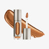 Eine teils silberne und teils transparente Tube Vision Flush Glow Majesty mit gold-bronze schimmerndem Inhalt vor weißem Hintergrund.