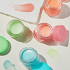 Vier bunte, geöffnete Tiegel der Laneige Lip Sleeping Mask EX mit Produktmustern auf hellem Hintergrund.
