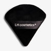 Der Powder Puff von LH Cosmetics ist ein schwarzer, dreieckiger Make-up-Puff, auf dessen Vorderseite der Markenname auf einem Band aufgedruckt ist.
