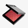 Das halb-geöffnete Rouge At First Blush von Mesauda Beauty in einer quadratischen Produktschale und eingeprägtem M-Muster.
