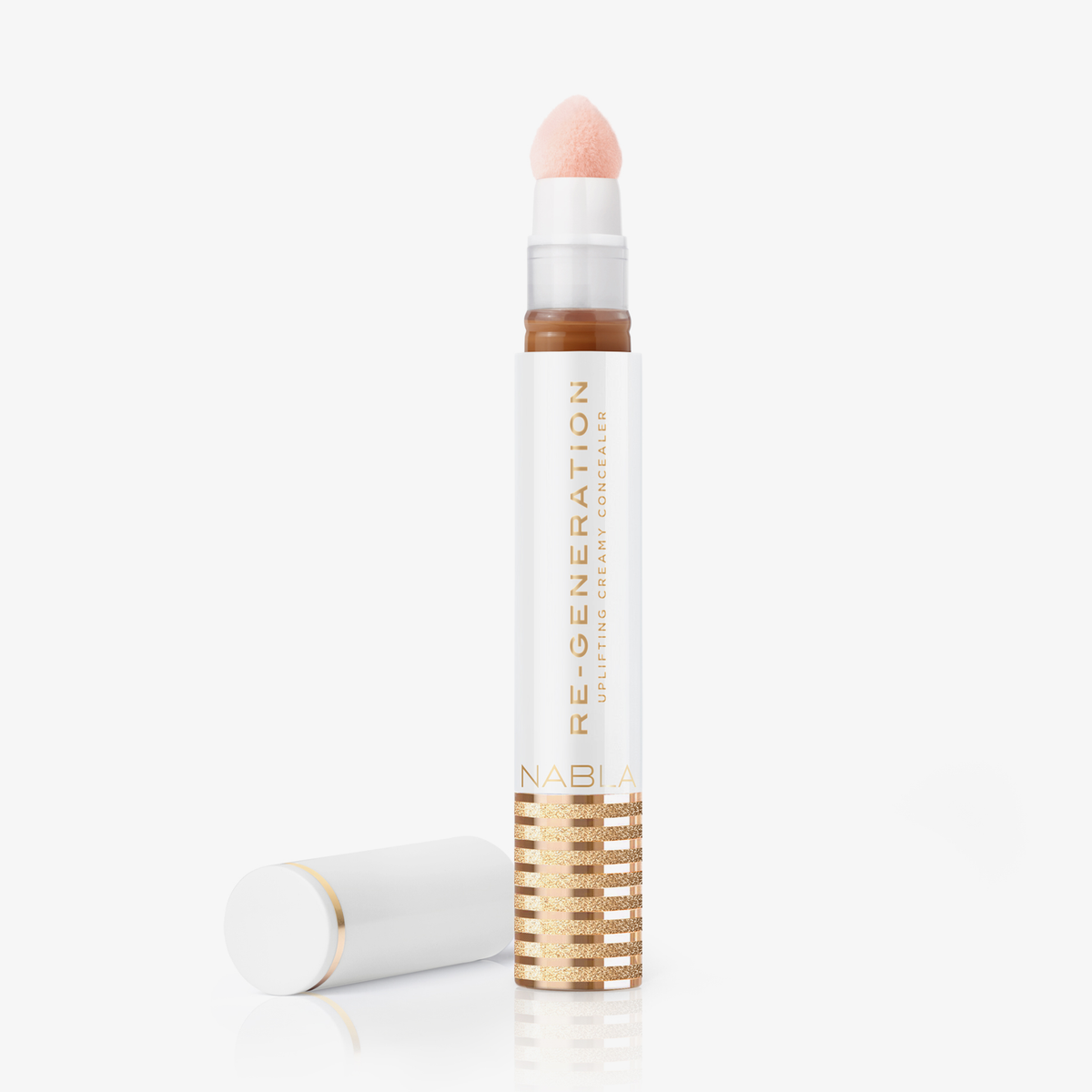 Eine weiß-goldene Tube Re-Generation Concealer in der Farbe Warm Honey mit einer Schwammspitze und der daneben platzierten Kappe.