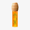 Eine Flasche NUXE Honey Lip Care Rêve de Miel mit einem Verschluss in Form einer Honiglöffel.