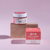 Tiegel und Schachtel der Collagen Face Cream präsentiert auf einem Holzblock mit pastellrosa Hintergrund.