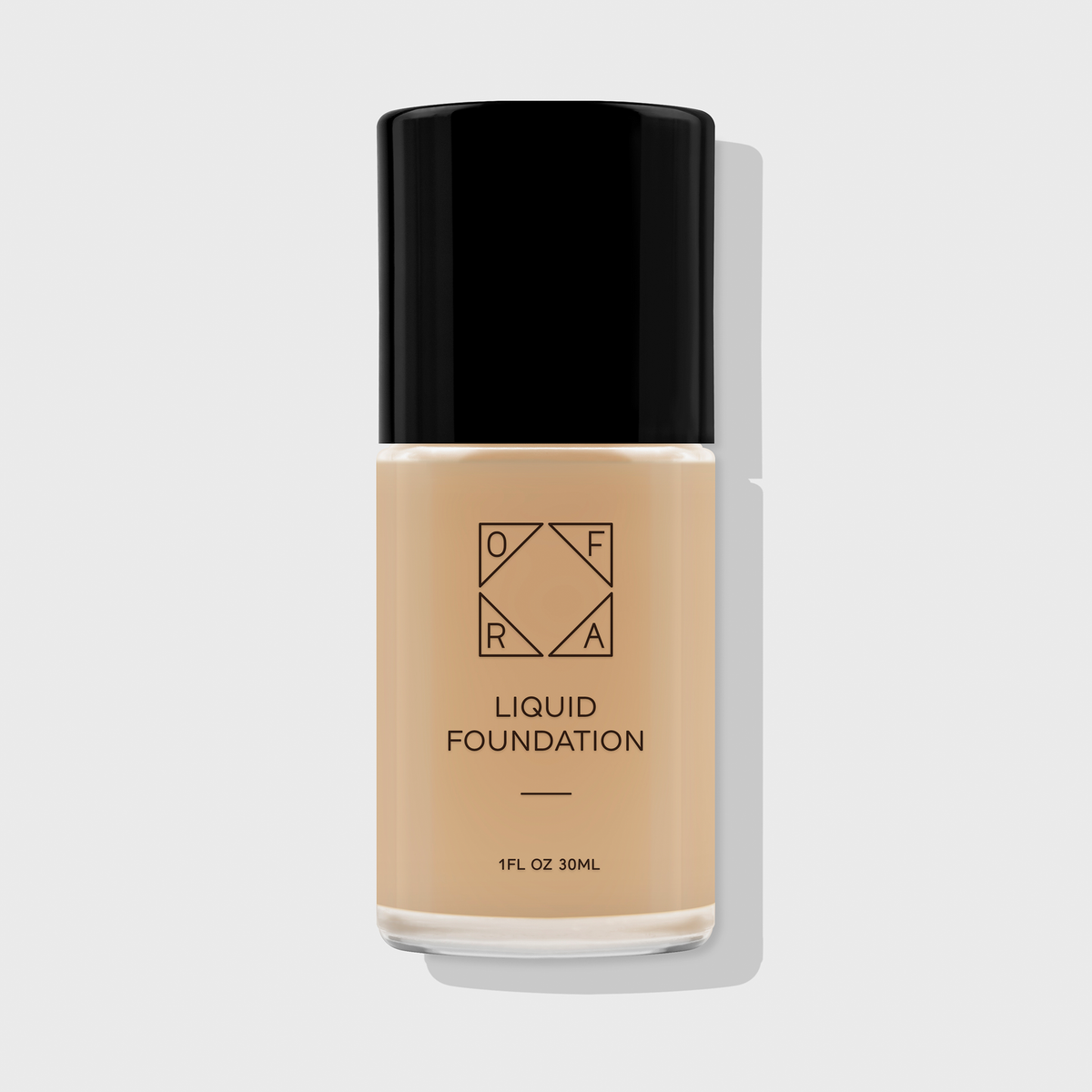 OFRA Liquid Foundation in der Nuance Bare in transparenter Glasflasche mit schwarzem Deckel und schwarzer Beschriftung, vor hellem Hintergrund.