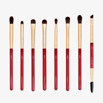 Das Ruby Complete Eye Brush Set enthält acht Pinsel mit roten und goldenen Griffen, die in einer Reihe auf weißem Hintergrund angeordnet sind.