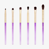 Das Amethyst Detail Brush Set enthält sechs Make-up-Pinsel mit goldenen Zwingen und violetten Farbverlaufsgriffen, die in einer Reihe auf weißem Hintergrund angeordnet sind.