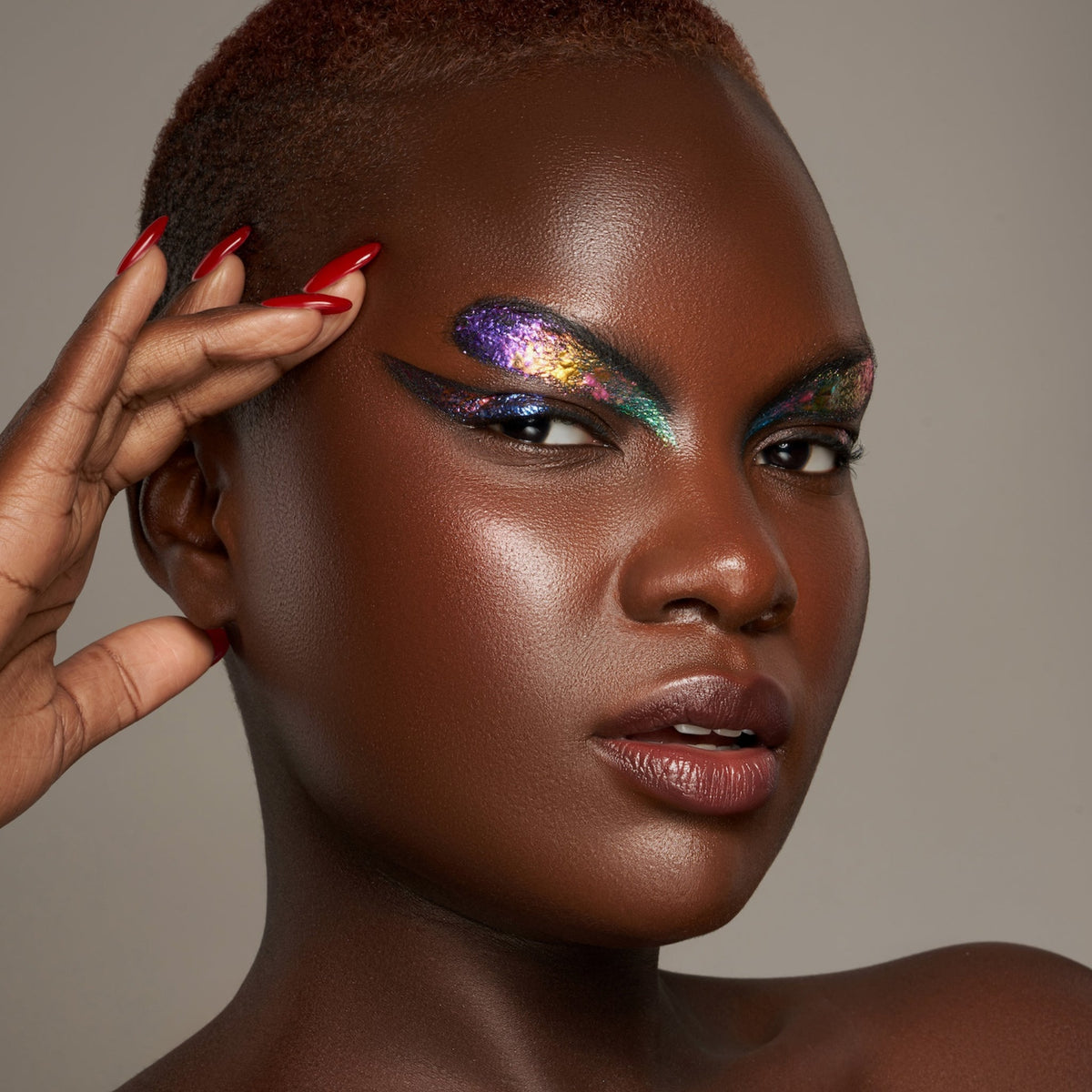 Person mit geschlossenen Augen und dunklem Hautton präsentiert schimmernden, irisierenden Make-up-Look mit den Infinite Chrome Flakes Moonlight.