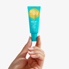 Eine Hand hält eine blaue Tube Bondi Sands Lip Balm SPF 50+ Sweet Vanilla vor einem weißen Hintergrund