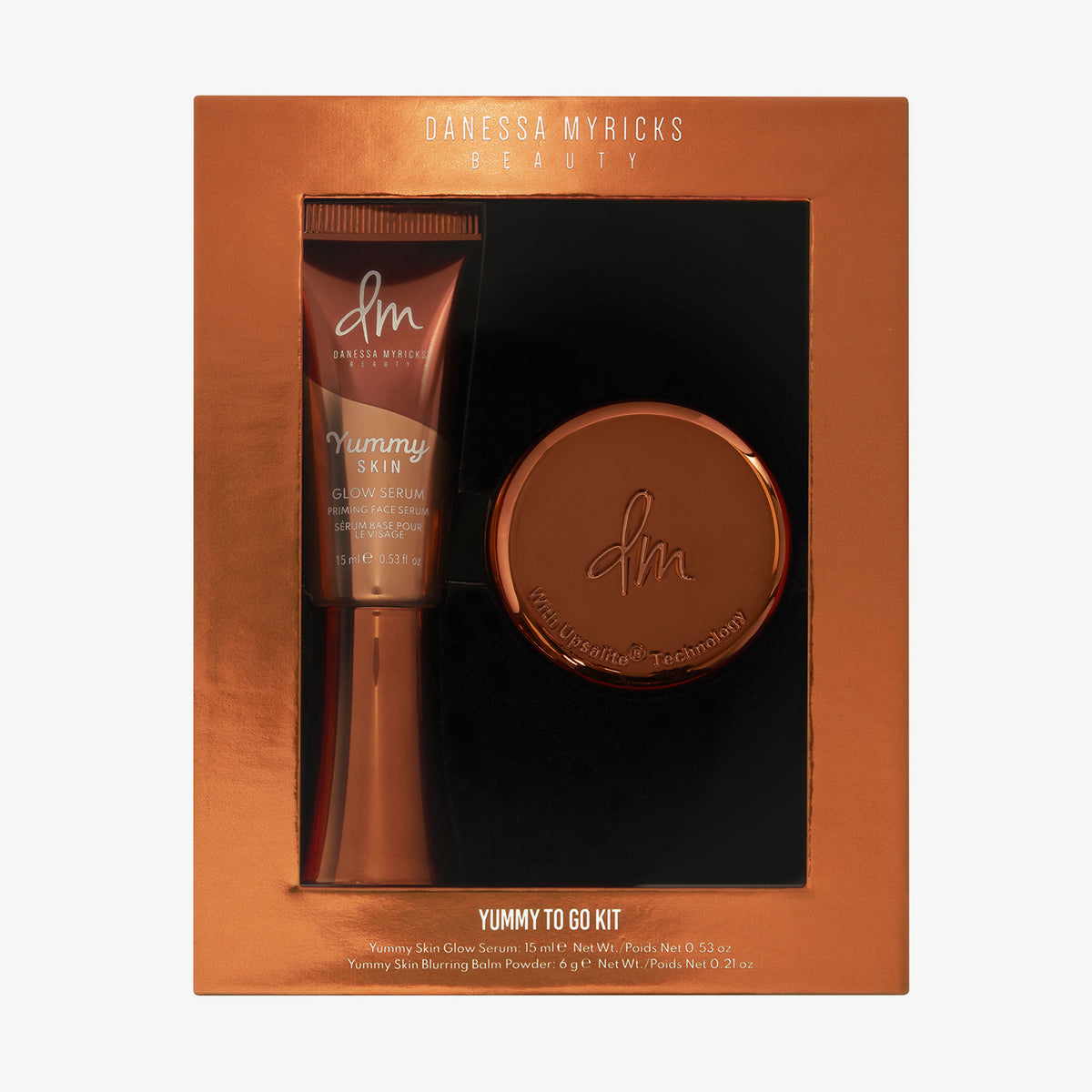 Danessa Myricks Beauty Yummy To Go Kit mit Yummy Skin Glow Serum und Blurring Balm Powder in einer kupferfarbenen Verpackung.
