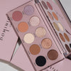 Die Essential Palette mit zwölf neutralen und schimmernden Farbtönen ist geöffnet und auf einer rosa Oberfläche präsentiert.