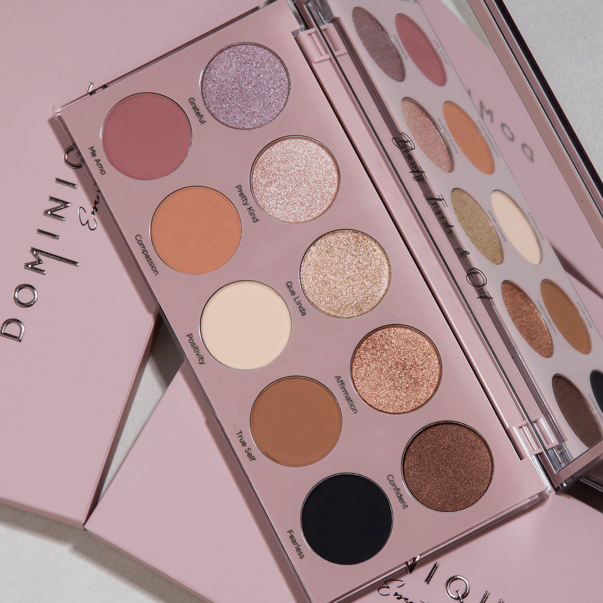 Die Essential Palette mit zwölf neutralen und schimmernden Farbtönen ist geöffnet und auf einer rosa Oberfläche präsentiert.