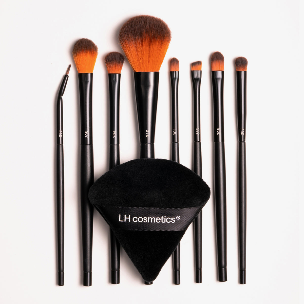 Infinity Tool Box bestehend aus acht schwarzen Make-up-Pinseln mit orange-braunen Borsten und einem schwarzen Puderkissen.