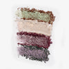 Auf weißem Hintergrund werden vier schimmernde Lidschattenmuster in Grün, Beige, Burgunderrot und Lila aus der Shimmer Saga Palette von LH Cosmetics angezeigt.