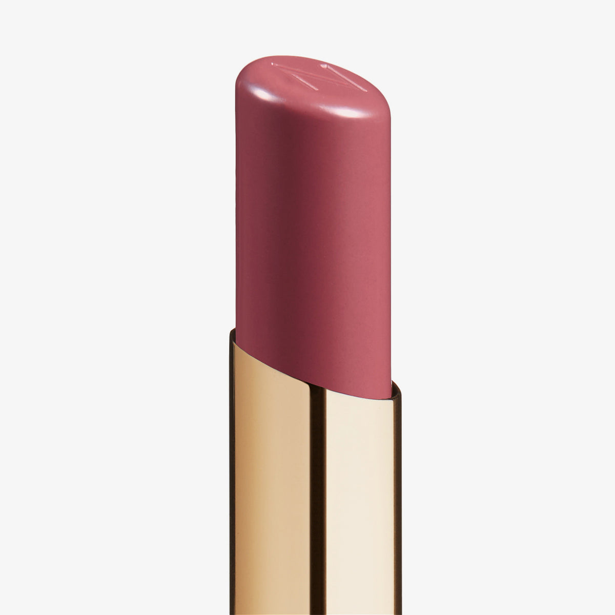 Eine Nahaufnahme des Beyond Jelly Lipstick in der Farbe Dea in einer glänzenden goldenen Hülse vor weißem Hintergrund.