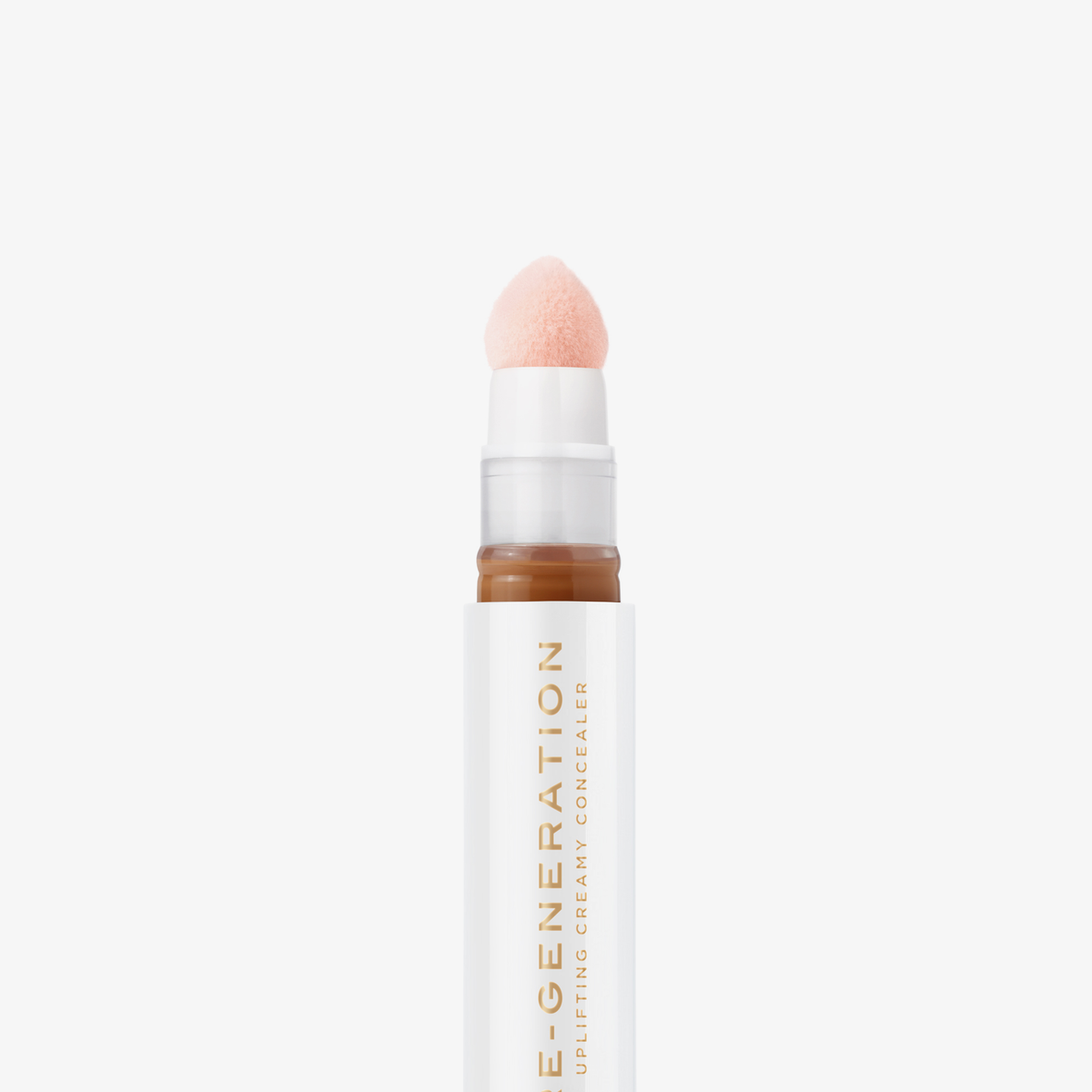 Nahaufnahme der weiß-goldenen Tube Re-Generation Concealer in der Farbe Warm Honey mit rosafarbener Schwammspitze – für gebräunte Haut mit warmem Unterton.