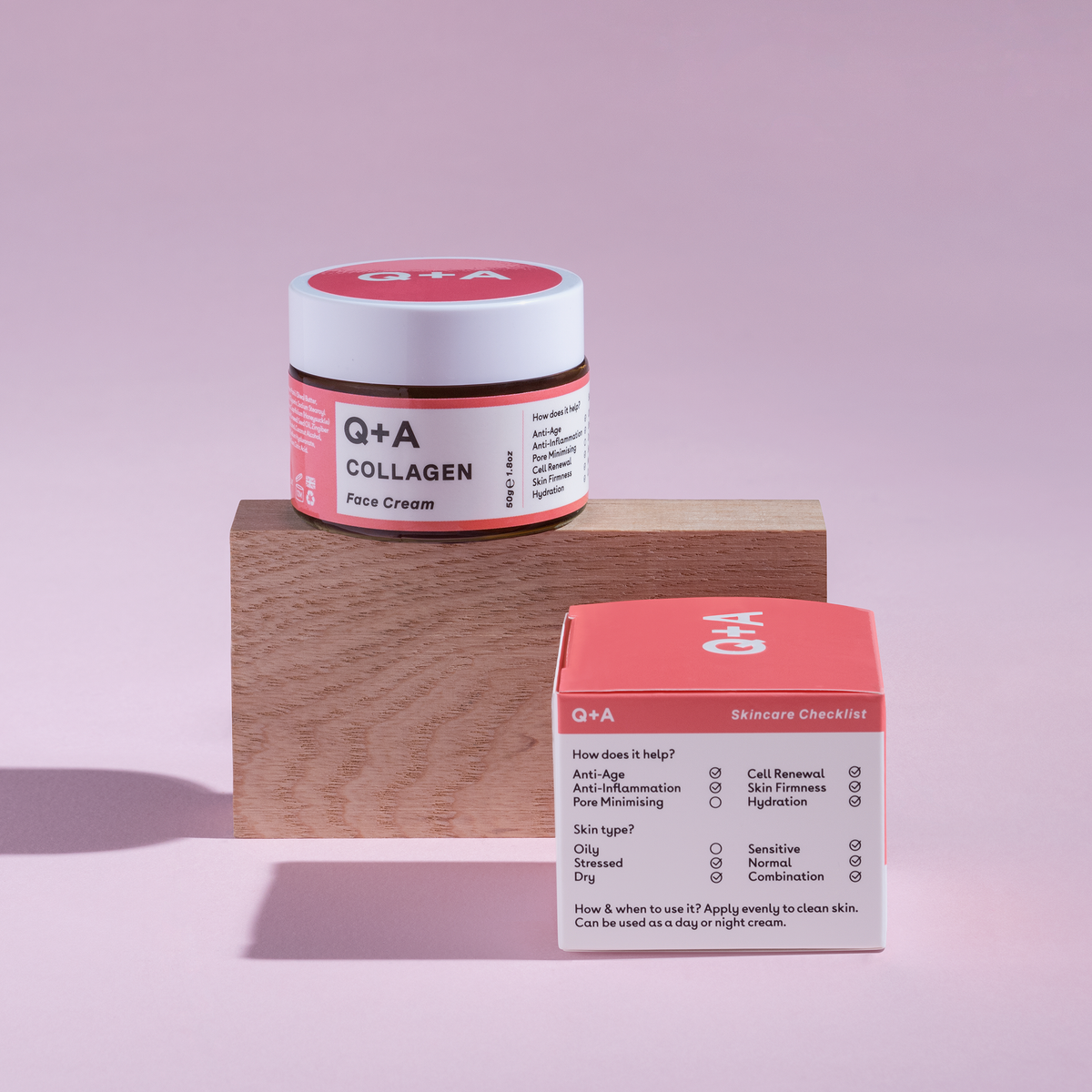 Ein Tiegel und eine Schachtel Collagen Face Cream präsentiert auf einem Holzblock vor einem rosa Hintergrund.