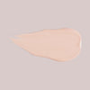 Ein Klecks Wide Awake Full Coverage Concealer, eine hellbeige Flüssigkeit, auf hellgrauem Hintergrund.