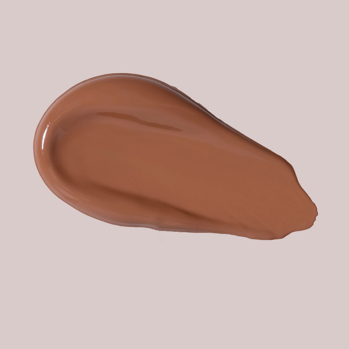 Ein glatter Farbstreifen des Wide Awake Full Coverage Concealer in einem satten Braunton ist auf einem hellbeigen Hintergrund verteilt.