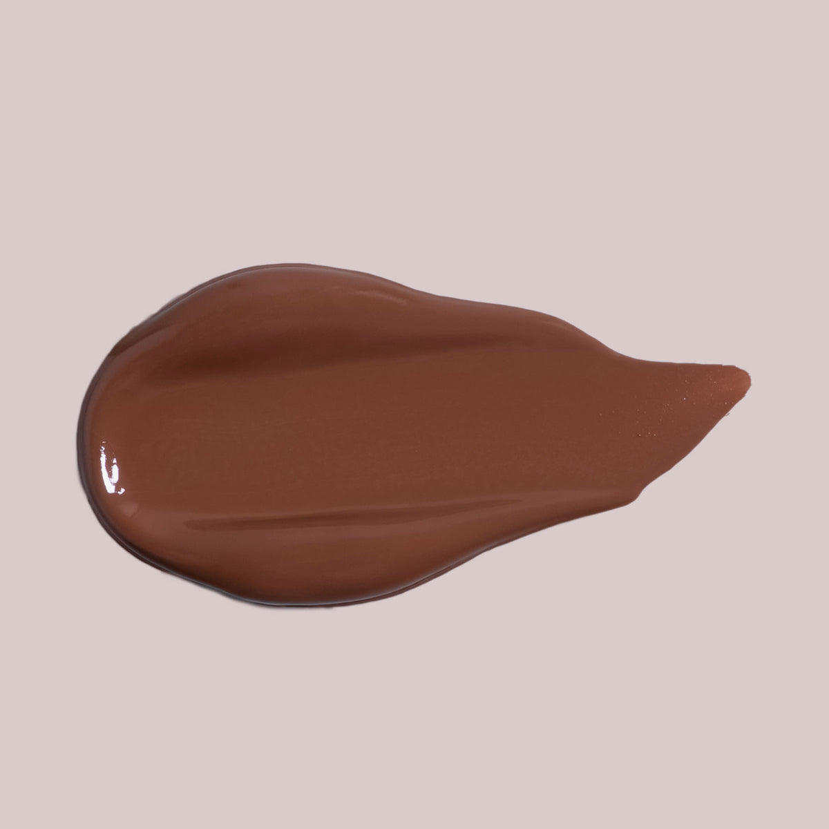 Ein glatter Farbstreifen des Wide Awake Full Coverage Concealer in Braun, abgebildet auf einem hellbeigen Hintergrund.