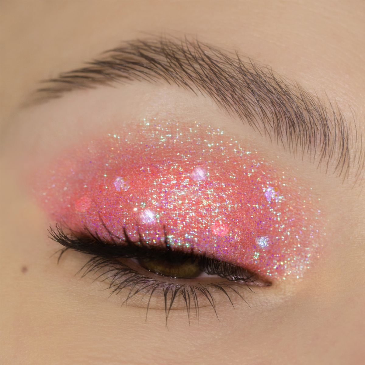 Ein geschlossenes Auge, geschmückt mit schimmerndem rosa Glitzerlidschatten aus der Miami Lights Glitter Palette und langen Wimpern.