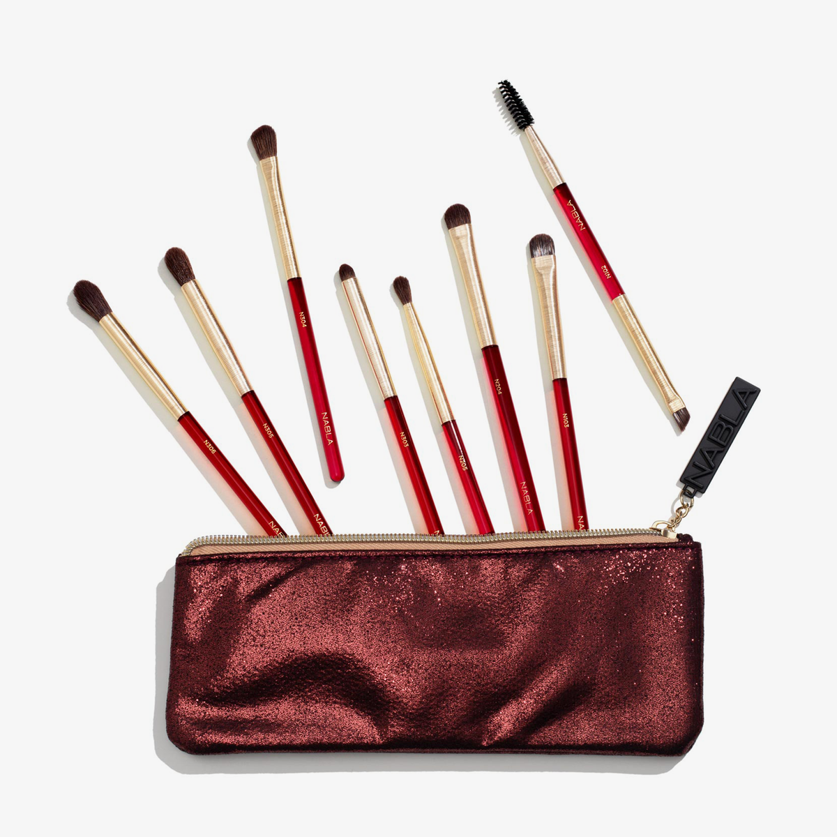 Das Ruby Complete Eye Brush Set enthält neun rote und goldene Pinsel in einem glitzernden burgunderfarbenen Beutel auf weißem Hintergrund.