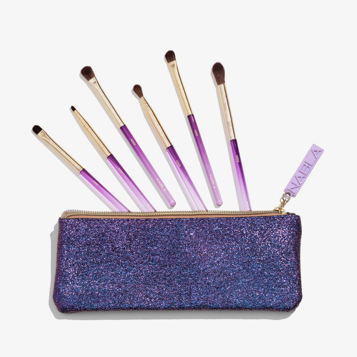 Das Amethyst Detail Brush Set enthält sechs Make-up-Pinsel mit violettem Griff, die über einem glitzernden violetten Beutel mit Reißverschluss präsentiert werden.