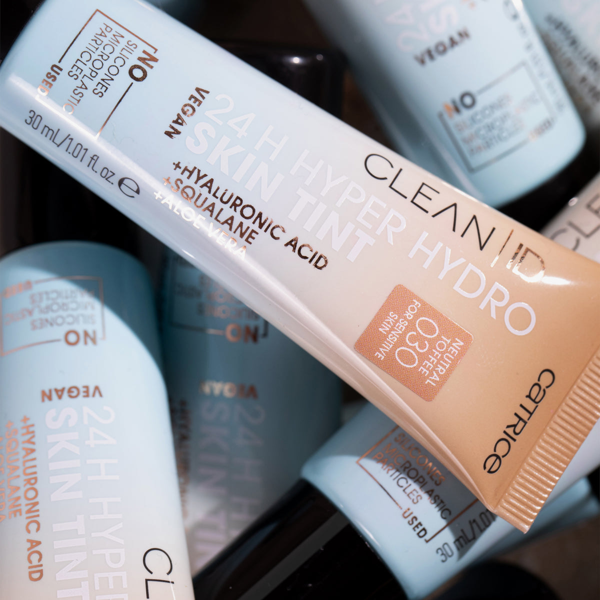 Mehrere Tuben Clean ID 24H Hyper Hydro Skin Tint unsortiert übereinander gestapelt.