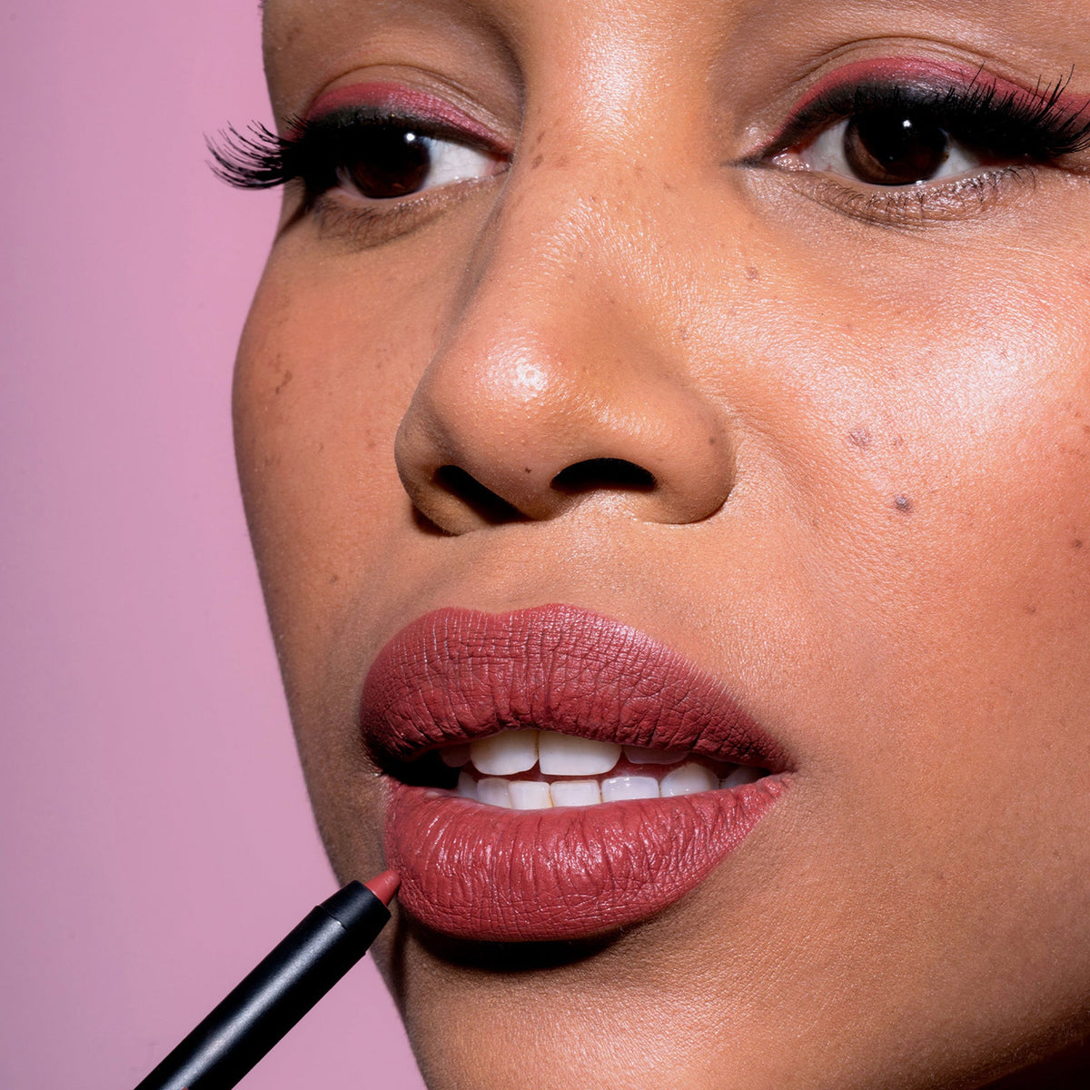 Eine Frau trägt den Crayon Lipliner in Cherry von LH Cosmetics auf ihre Lippen auf.