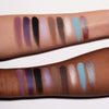 Zwei Arme mit unterschiedlichen Hauttönen zeigen lilane, schwarze, grau und beige Farbmuster der Daybreak Palette von LH Cosmetics.