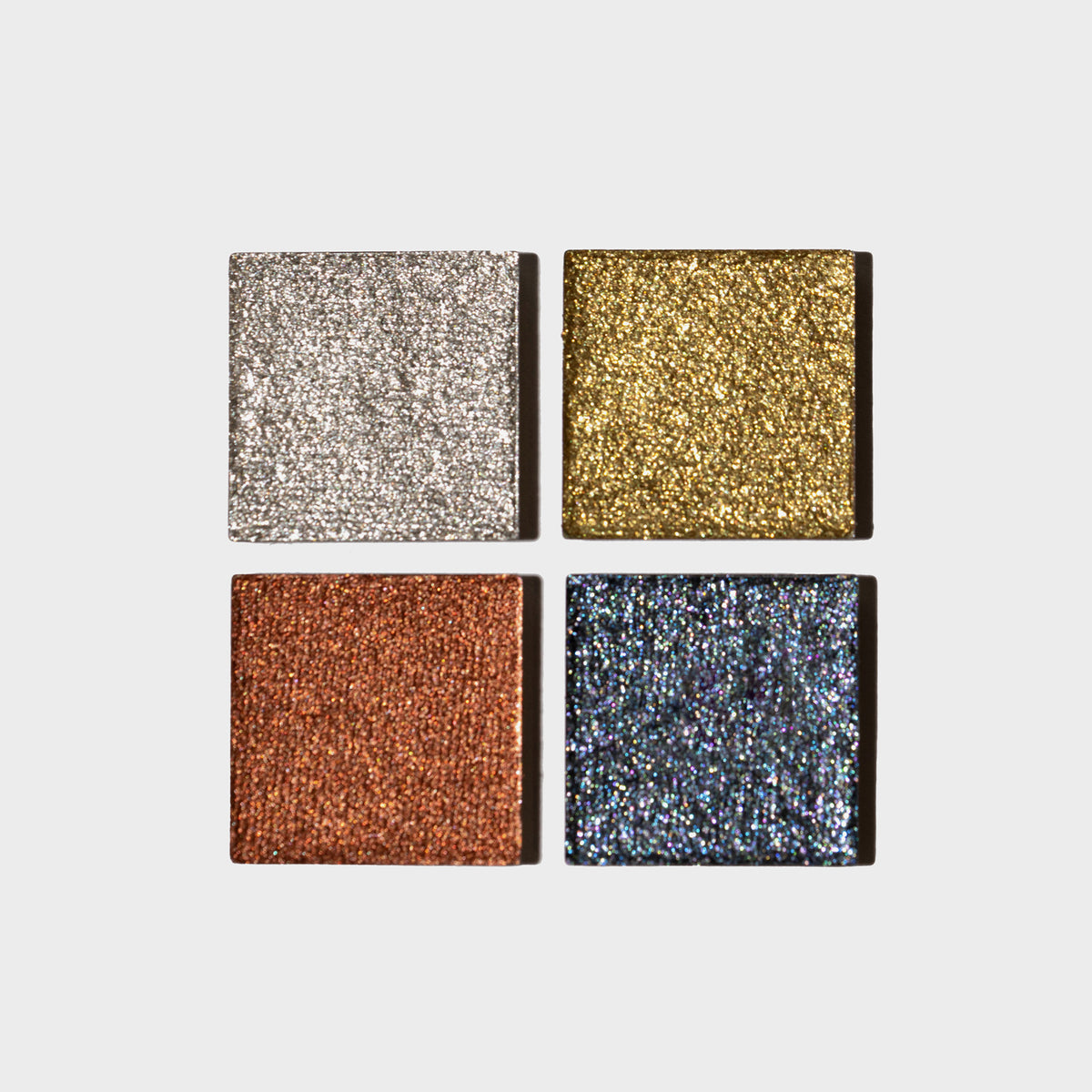 Vier Pfännchen der LH Cosmetics Basic Elements mit Glitzerlidschatten – Silber, Gold, Kupfer und Dunkelblau – auf weißem Hintergrund.