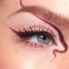 Nahaufnahme eines Auges mit kreativem dunkelrotem Eyeliner, kreiert mit dem LH Cosmetics Crayon Siren.