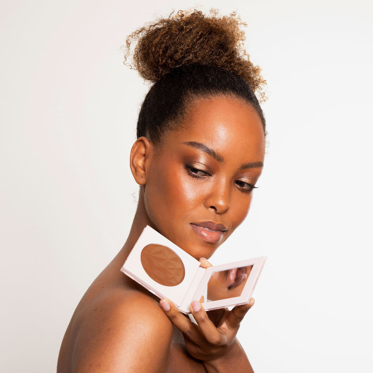 Eine Frau mit strahlendem warmen Make-up lächelt in die Kamera und einen Infinity Bronzer in der Farbe Forever von LH Cosmetics.