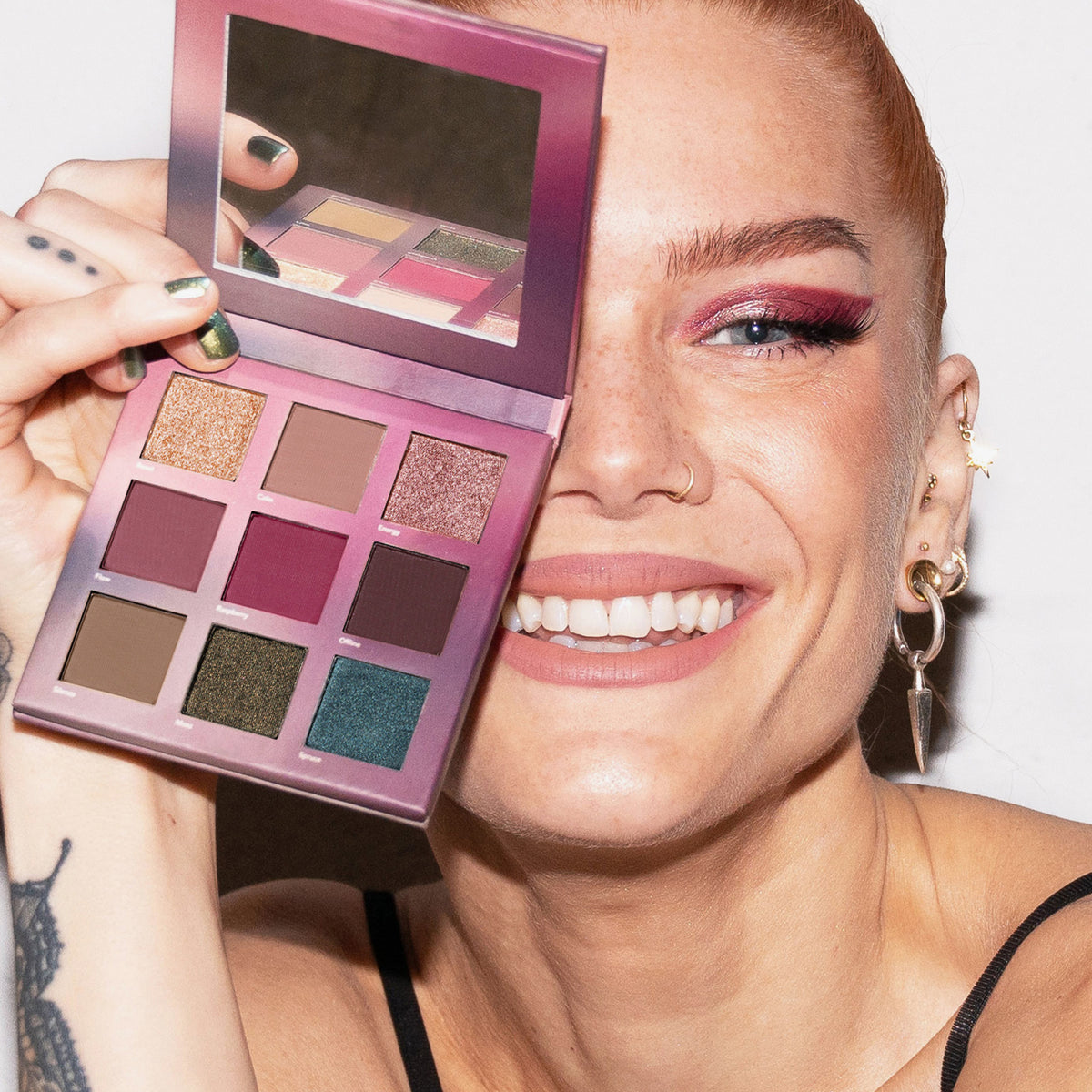 Eine lächelnde Frau hält die LH Cosmetics Reload Palette über ein Auge und präsentiert kräftiges rosa Make-up.