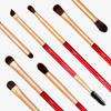 Das Ruby Complete Eye Brush Set mit roten und goldenen Pinseln und Bürsten ist diagonal auf einem weißen Hintergrund angeordnet.