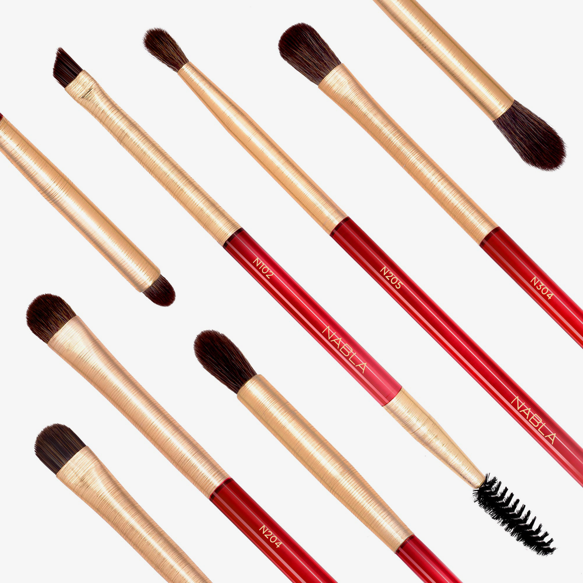 Das Ruby Complete Eye Brush Set mit roten und goldenen Pinseln und Bürsten ist diagonal auf einem weißen Hintergrund angeordnet.