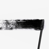 Eine Vicious™ Mascara-Bürste verteilt einen dicken, schwarzen Streifen Mascara auf einem weißen Hintergrund.