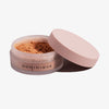 Offener Behälter mit Smooth & Blur Setting Powder mit beigem Deckel und der Aufschrift DOMINIQUE auf weißem Hintergrund.