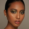 Person mit geschlossenen Augen und mittelbraunem Hautton präsentiert schimmernden, irisierenden Make-up-Look mit den Infinite Chrome Flakes Firefly.