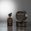 Flasche Snail Bee Ultimate Serum mit offenem Pipettenapplikator, neben 2 Snail Bee Eyepatch Tiegeln in grauer Umgebung