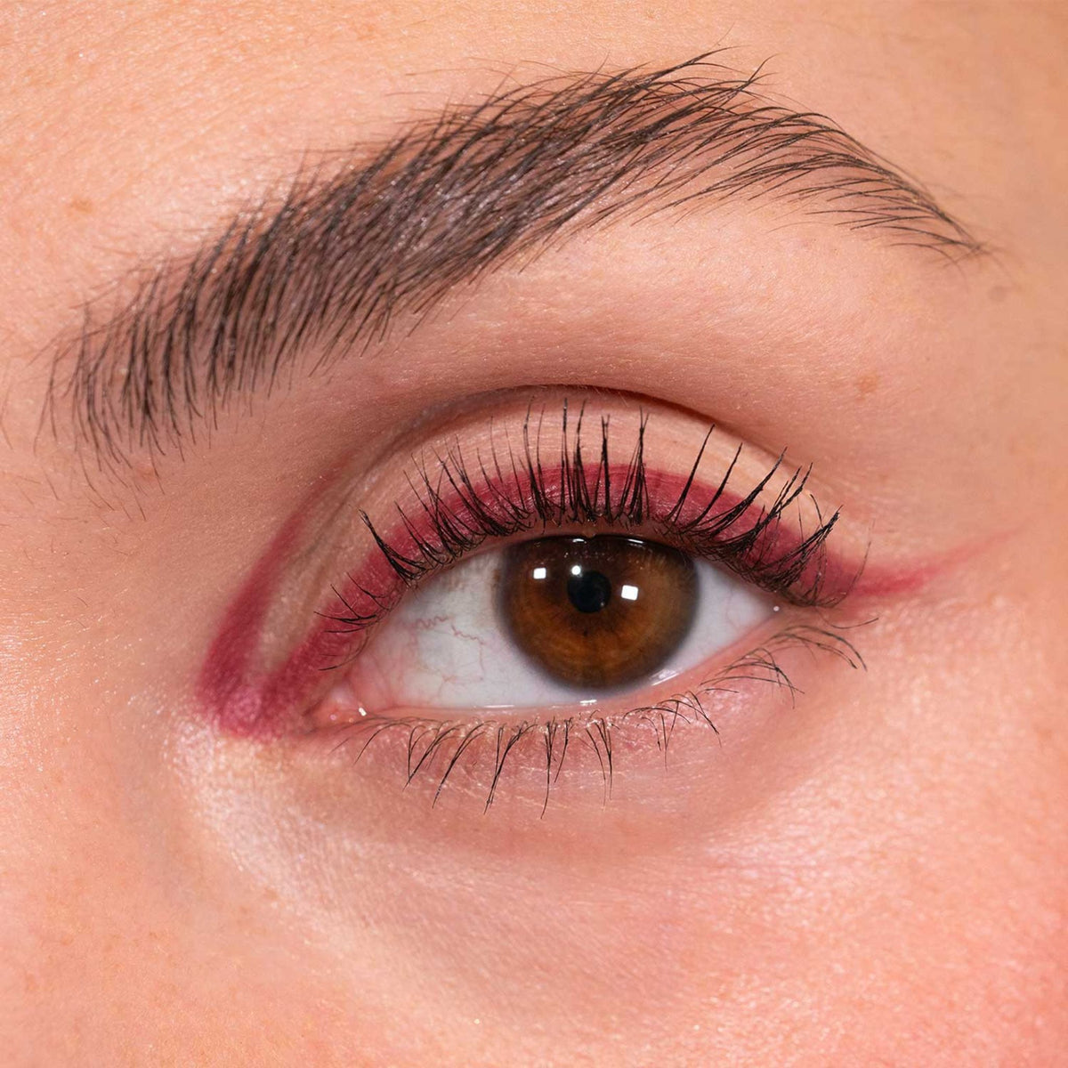 Nahaufnahme eines Auges mit kreativem rotem Eyeliner, kreiert mit dem LH Cosmetics Crayon Nugget.