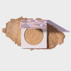 Infinity Bronzer Always von LH Cosmetics auf losem beige-braunem Puder auf weißem Hintergrund.