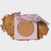 Infinity Bronzer Beyond von LH Cosmetics auf losem beige-braunem Puder auf weißem Hintergrund.