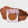 Infinity Bronzer Forever von LH Cosmetics auf losem dunkelm orange-braunem Puder auf weißem Hintergrund.