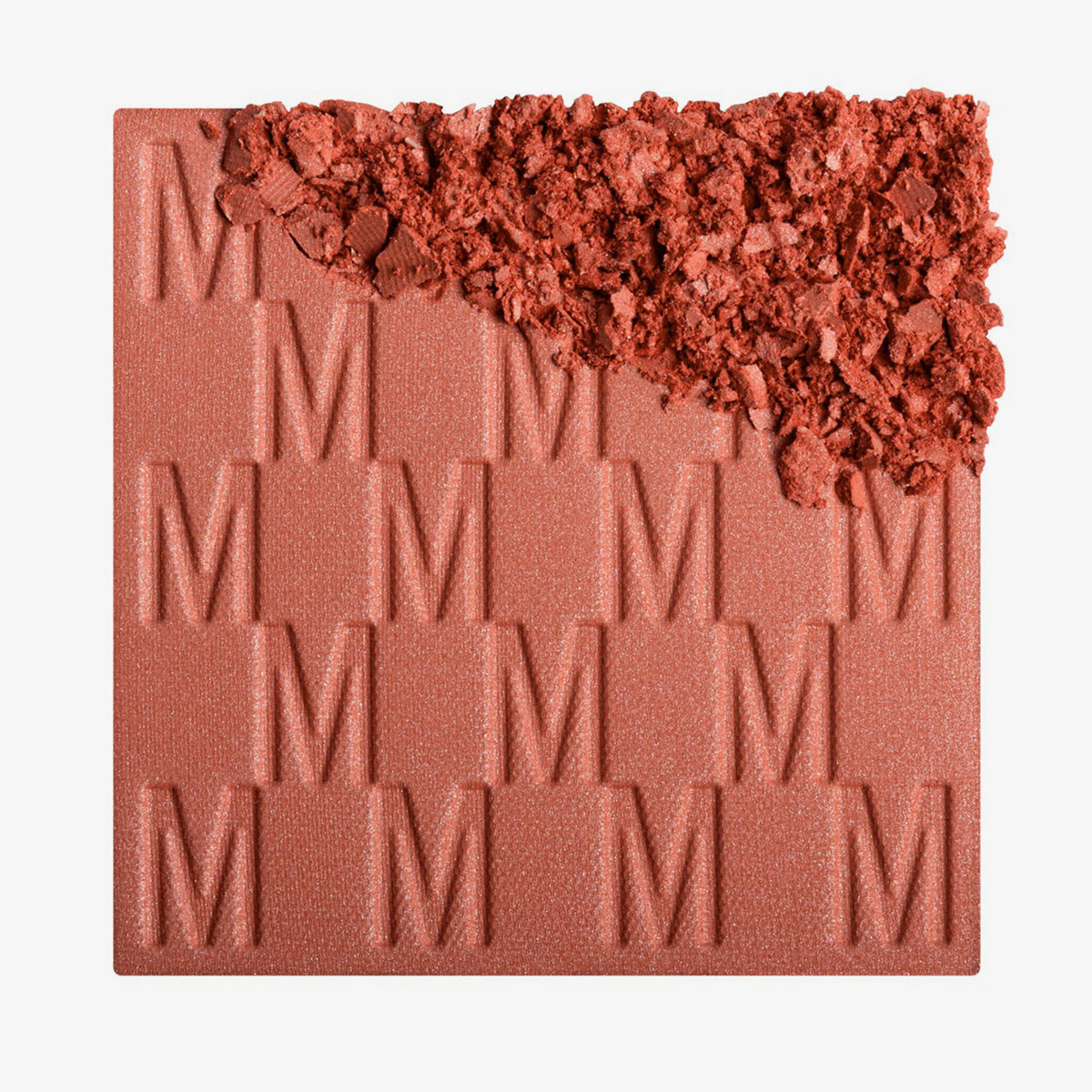 Das Rouge At First Blush von Mesauda Beauty mit eingeprägtem M-Muster, die obere, rechte Ecke ist in losem Puder zerkleinert dargestellt.
